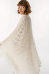 Ruana de punto color beige con cuello alto y flecos.