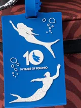 Bolso térmico (cooler bag) de gran tamaño, color marrón rojizo, con estampado mixto de leopardo y cebra. Posee manija superior y correa ajustable para hombro, ambas de cinta blanca con estampado negro de monograma.