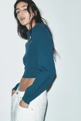 Sweater color crudo de tejido de punto acanalado, con cuello solapa abotonado y mangas largas abullonadas.