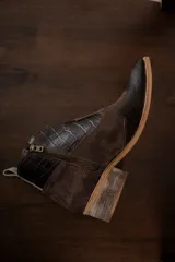 Botines de cuero marrón y blanco con diseño western, puntera redondeada y cierre lateral con cremallera. El talón tiene una tira de cuero para facilitar el calce.