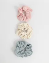 Set de tres scrunchies con textura acanalada en colores rosa, crema y celeste.
