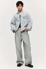 Pantalón jean gris claro, de corte holgado con pierna ancha y tiro bajo. Diseño clásico de cinco bolsillos con cierre frontal con cremallera y botón.