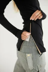 Blusa negra de tejido de punto con cuello alto y abertura en el pecho con cierre.