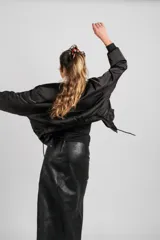 Falda larga de cuero negro, confeccionada con paneles rectangulares, de corte recto y cierre trasero.