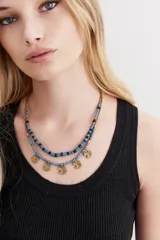 Collar doble con cuentas azules y negras, y dijes dorados con forma de ancla.