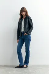 Chaqueta negra de eco cuero con detalles de tul en mangas y hombros, cierre frontal con cremallera dorada y corte ajustado.