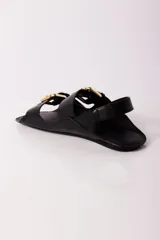 Sandalias negras de cuero con dos tiras anchas sobre el empeine, hebillas doradas y tira trasera.