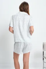 Conjunto de pijama de viscosa color blanco con estampado floral celeste, compuesto por una camisa de manga corta con cuello y botones, y un short con cintura elástica.