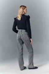 Jean tiro alto de denim negro rígido, lavado gris localizado con bigotes, pierna recta y apliques laterales de lentejuelas o tachas.