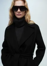 Abrigo negro oversize con cuello de solapa, manga larga y cinturón desmontable.