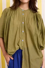 Camisa verde militar de algodón con mangas murciélago, corte holgado y botones florales azules.