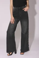 Pantalón de jean gris oscuro de corte acampanado, con tachas metálicas plateadas en los laterales.