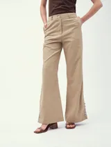 Pantalón de vestir color beige, de corte palazzo, con cintura alta y detalle de botones en el ruedo.