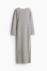 Vestido largo de punto texturizado a rayas horizontales en blanco y negro. Tiene cuello redondo, mangas largas y tajo lateral pronunciado.