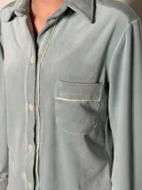 Pijama celeste de terciopelo, compuesto por una camisa de manga larga con botones y vivo blanco, bolsillo en el pecho y un pantalón recto con elástico en la cintura.