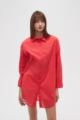 Camisa blanca de algodón con cuello clásico, corte holgado, cierre frontal con botones y mangas largas.