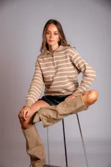 Sweater de punto color beige con rayas horizontales blancas, cuello polo con cierre de cremallera y mangas largas.
