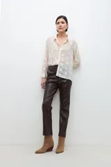 Camisa negra traslúcida con bordado floral, cuello clásico, cierre con botones y mangas largas con puños abotonados.