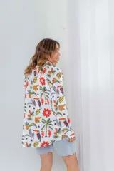 Camisa blanca con estampado de flores rojas, palmeras, piñas y tucanes.