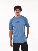 Remera negra de corte oversized con estampado circular en el pecho que incluye una palmera, una ola y la palabra 'Paradise'.