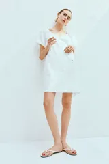 Vestido corto evasé de algodón blanco, con mangas globo cortas de diseño raglán, escote redondo con cordón para ajustar y corte holgado.