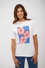 Remera blanca de manga corta con cuello redondo y un estampado frontal de tres flores rosadas sobre un fondo azul.