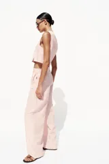 Pantalón de vestir color rosa pálido, de tiro alto, con pinzas delanteras, bolsillos laterales, pierna ancha y cierre frontal con cremallera y botón.