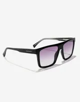 Lentes de sol Hawkers unisex, modelo Aspen, con montura cuadrada negra y lentes degradadas de negro a violeta.