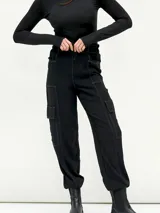 Pantalón negro de corte holgado con cintura elástica ajustable con cordón, bolsillos laterales y bolsillos tipo cargo en los laterales de las piernas.