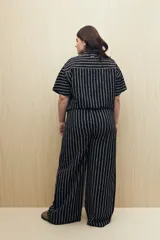 Pantalón ancho de viscosa con estampado a rayas verticales blancas sobre fondo negro, cintura elastizada y caída fluida.