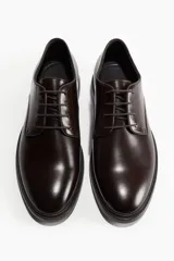 Zapato de vestir Derby de cuero color marrón oscuro, con cordones y suela plana.