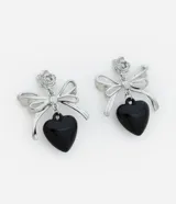 Aros colgantes plateados con forma de moño y corazón negro.