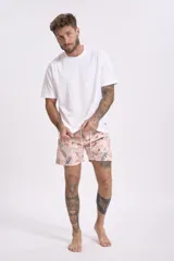 Short de baño color rosa con estampado de hojas y flores en tonos verdes, marrones y blancos.