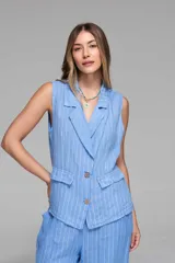 Chaleco celeste con rayas verticales blancas, cuello solapa, cierre frontal con botones de madera y bolsillos delanteros con solapa.