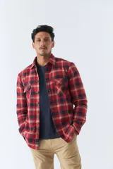 Sobrecamisa de algodón para hombre con interior de corderito, estampado a cuadros en tonos negro, blanco y azul. Tiene cierre de botones, bolsillos tipo cartera y logo en goma. El modelo usa talle M.