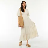 Vestido largo color beige, con escote en V, mangas cortas y falda con volantes.