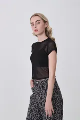 Remera de manga corta, cuello redondo y corte ajustado al cuerpo, confeccionada en tejido de poliéster con estampado de camuflaje en tonos verde militar, beige y marrón.