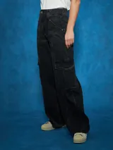 Pantalón de jean de tiro alto, color azul medio, con corte ancho y pierna recta. Presenta costuras marcadas en el centro de las piernas y bolsillos cargo a los lados.