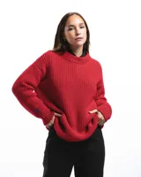 Sweater unisex de lana merino fina color rojo, con cuello redondo y corte relajado. Presenta un motivo inspirado en la técnica de zurcido visible.