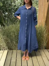Vestido camisero amplio y largo de lino color azul, con botones de nácar, cuello camisero y bolsillos laterales.