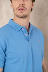 Chomba azul con cuello clásico, tapeta de dos botones y logo bordado en el pecho.