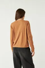 Remera manga larga color marrón con cuello redondo y bordado al frente sobre la izquierda.