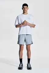 Remera deportiva blanca de corte boxy, confeccionada en tejido funcional DryMove™ que ayuda a absorber el sudor. Tiene cuello redondo ribeteado y hombros levemente caídos. Estampado en el frente con flechas y el número 012 en color celeste.