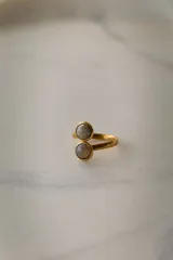 Anillo dorado ajustable de acero quirúrgico hipoalergénico con dos piedras redondas de color violeta.