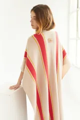 Ruana artesanal color beige con rayas horizontales rojas y amarillas, y flecos en el borde inferior.