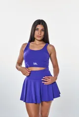 Conjunto deportivo violeta compuesto por un top corto con logo "bk." y una falda corta acampanada.