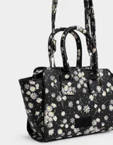 Cartera mini city de cuerina negra estampada con flores blancas. Tiene correa desmontable y doble asa corta.