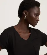 Blusa blanca de algodón con cuello en V, manga corta y bolsillo frontal.