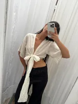 Top de lino color crudo con mangas amplias y lazo versátil para atar al frente o cruzarlo y ajustarlo atrás.
