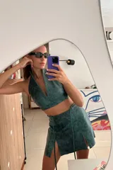 Top corto verde azulado de cuero ovino vintage, con cuello halter y espalda descubierta. Se cierra en la espalda con una hebilla metálica.